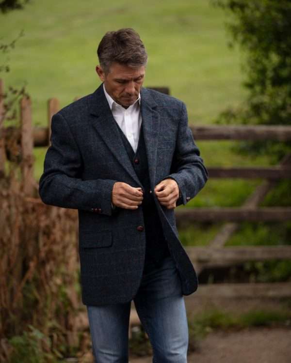 1T1A0001 scaled 1 These world famous Harris Tweed jackets, are superbly tailored, hard wearing and warm. When purchasing one of these jackets you are guaranteed exceptional quality. By law Harris Tweed must come from the Outer Hebrides, and be hand woven from local wool. Supplied by Harris Tweed Scotland from 100% pure virgin wool, dyed, spun and finished in the Western Isles of Scotland. Hand-woven by crofters in their own homes on the islands of Lewis, Harris, Uist and Barra. They are single breasted with two leather button fastening, and can be worn as a casual jacket or with a shirt and tie. Other specifications include side vents, two front pockets with flaps, Four interior pockets, three button leather cuff and Fully lined. Spare Button Leather buttons included. Dress with matching waistcoat for an extremely stylish look perfect for weddings and the races. All our tweeds are stamped with the authentic, official gold crossed orb mark of the Harris Tweed Authority.