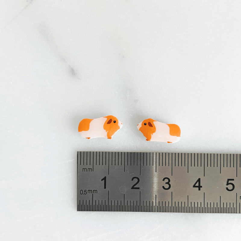 ruler size reference of gold and white guinea pig earrings
