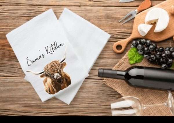 Highland cow illustration on a tea towel, personalised with name of your choice in a decorative font.