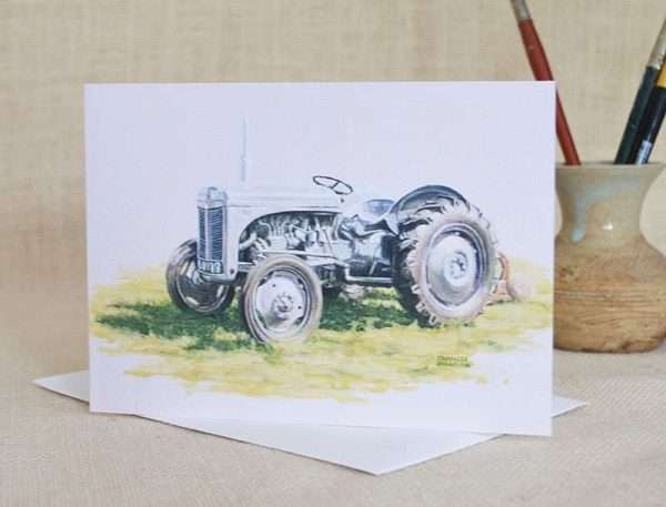 Grey Ferguson Tractor Art greetings card. Oblong, blank and viewed standin on envelope with small vase containing paint brushes in the background