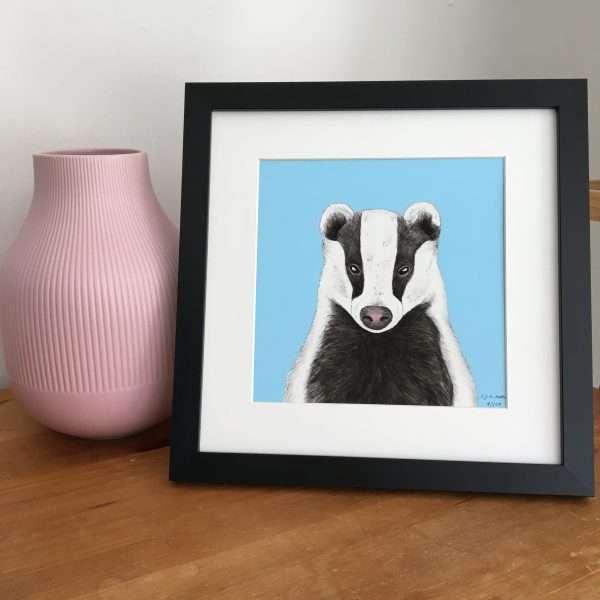 Badger Blk Frame Scene SQ scaled 10" x 10" art print of my original watercolour, fine liner and pencil illustration of a badger on a colourful​ blue background.