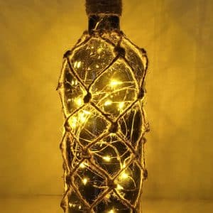 lit up green glass wine bottle with jute twine braiding in a diamond pattern. Jute twine wound down the bottle neck. Jute twine wound around the bottom of the bottle. Cork LED lights