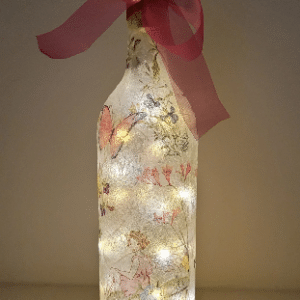 Lit up standard wine bottle with fairy detail Cork LED lights, pink bow tied around the neck