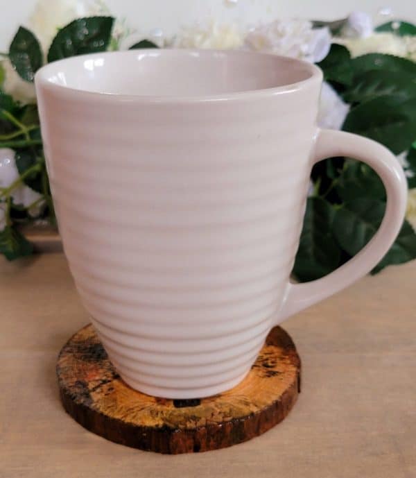 white mug sitting on a round wood slice coaster